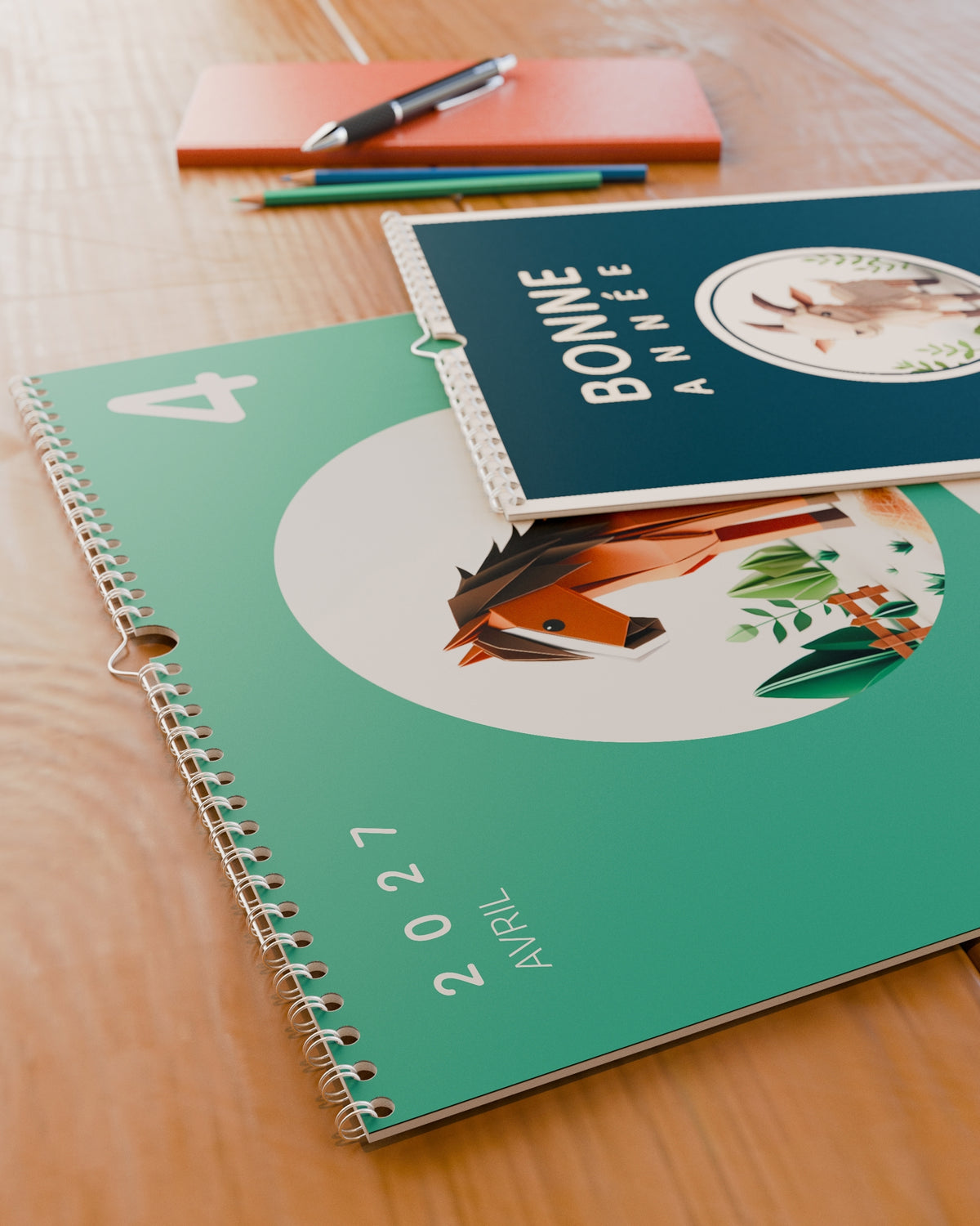 Gros plan sur la reliure spirale et le grain du papier du calendrier mural Bonne Année 2027, posé sur un bureau en bois.