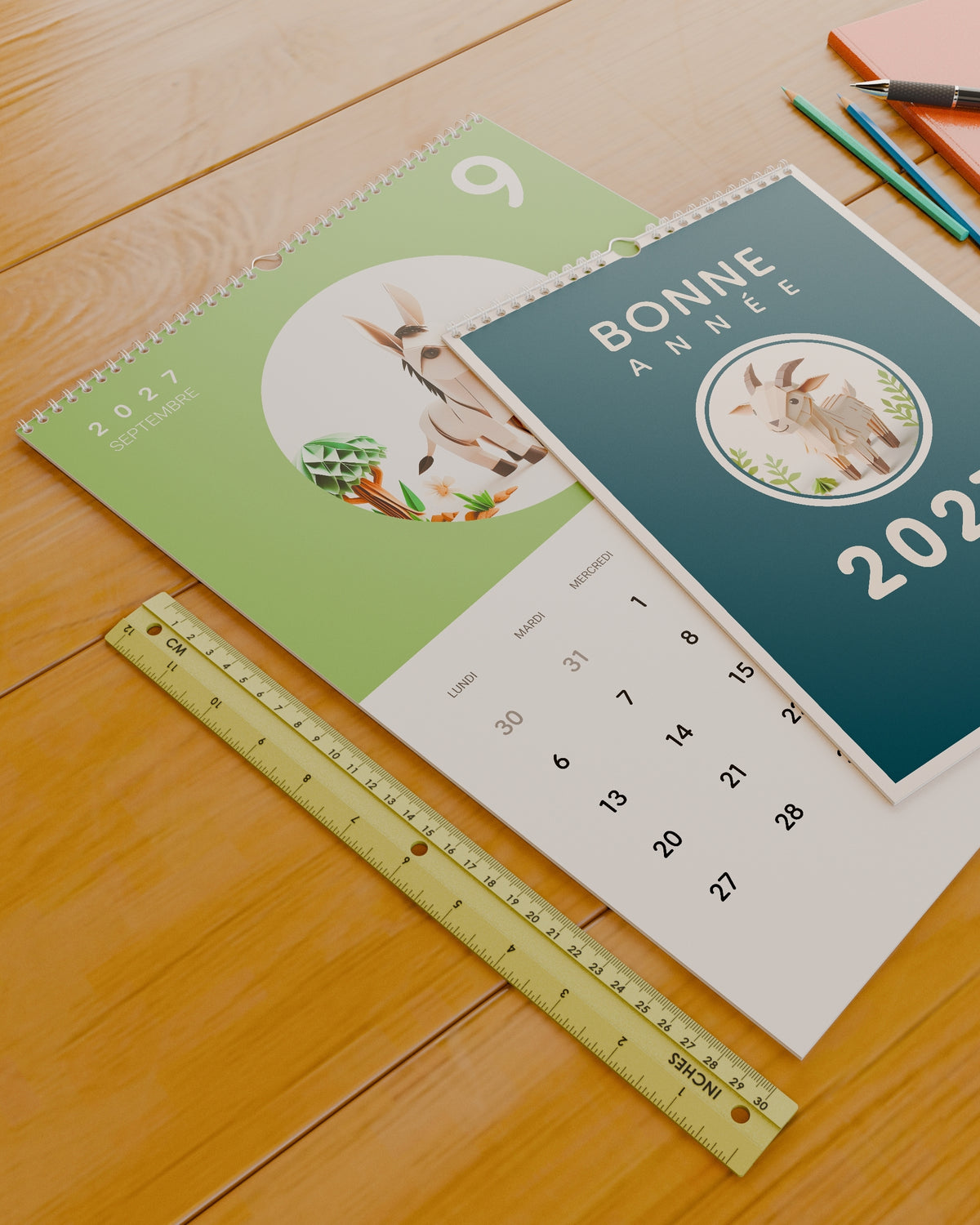 Calendrier mural Bonne Année 2027 posé sur un bureau à côté d'une règle de 30 cm, pour donner un repère d'échelle.