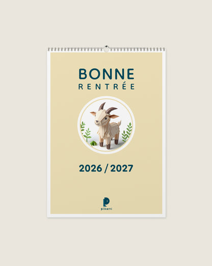 Calendrier mural à reliure spirale, couverture crème portant le titre Bonne Rentrée 2026 / 2027 et une chèvre en papier plié dans un médaillon rond.