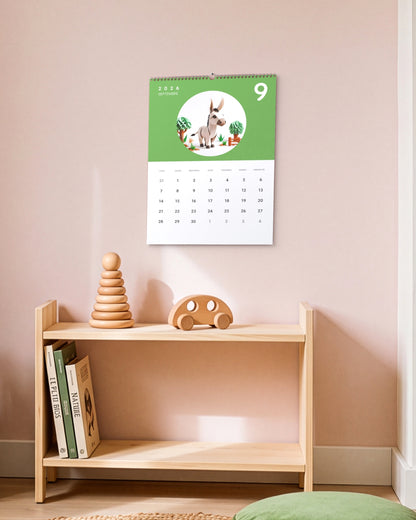 Calendrier accroché au mur rose au-dessus d'une étagère basse en bois avec jouets et livres d'enfant, ouvert sur septembre : un âne en papier plié sur fond vert.