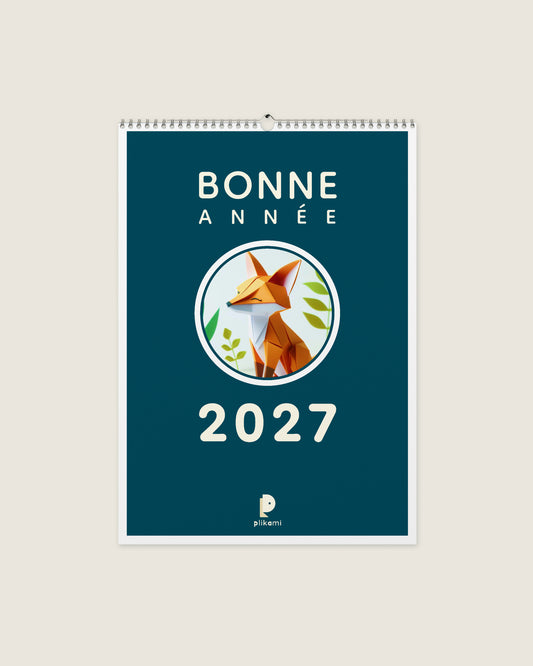 Calendrier mural à reliure spirale, couverture bleu canard portant le titre Bonne Année 2027 et un renard en papier plié dans un médaillon rond.
