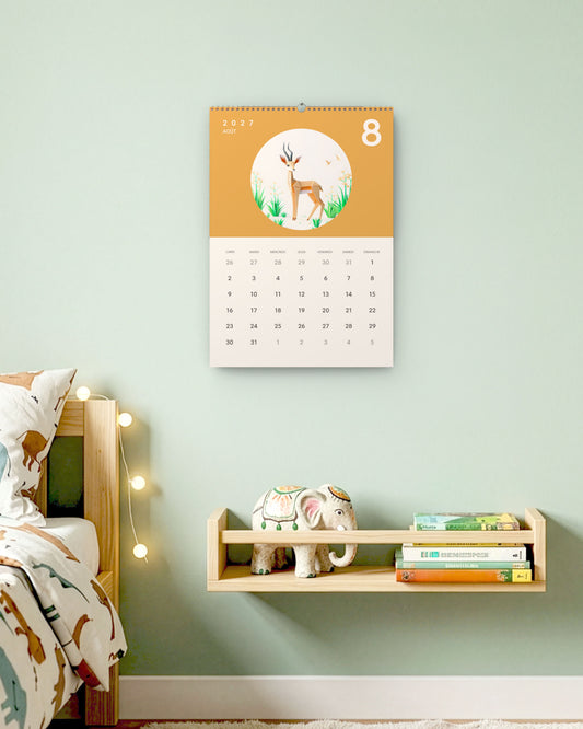 Calendrier accroché au mur vert d'eau d'une chambre d'enfant, au-dessus d'une étagère à livres, ouvert sur août : une gazelle en papier plié sur fond ocre.